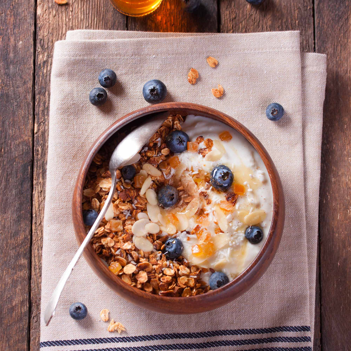 Ciotola con yogurt, chufa, mirtilli e mandorle a lamelle, vista dall’alto.